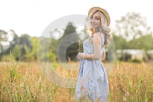 Rural, rural life. Walking through the meadow blonde young woman in a hat. Summertime