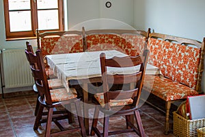 Rural living room of a country house with some wooden chairs, a sofa and a table with a tablecloth. Cozy and antique place