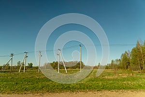 Rural llate spring landscape. Green field and power line along the road. Russian Country side