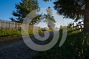 Rural macadam road that runs between wooden fences