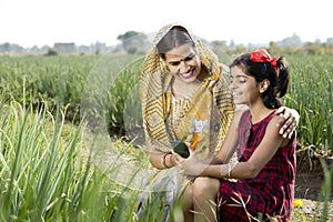 Rural mother and daughter using mobile phone on agriculture field