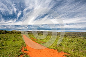 Rural orange dirt road with blue sky and far horizon