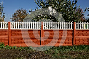 Rural red white concrete fence in grass on the street