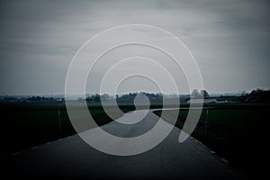 A rural road across the farmlands on a dark and gloomy winter day in southern Sweden