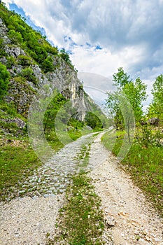 Rural road with grass, stones and cliffs