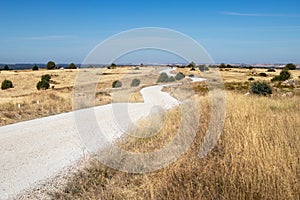 Rural road in the Spanish countryside among agricultural fields, after wheat harvest season. Cars driving on a dusty unsealed road