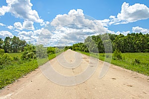 Rural road stretches into the distance, through the fields and woods