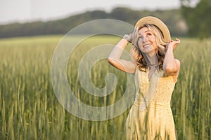 Rural, rural life. Walking through the meadow blonde young woman in a hat. Summertime