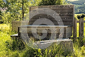 A rural, rustic bench with weathered and worn public info board in the countryside summertime