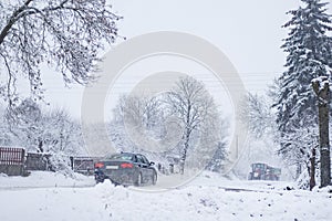 Rural scene with car driving  after heavy snowfall, transportation in winter, road covered in snow,  weather problems, country in