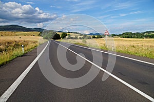 Rural scenery with empty road and traffic sign right bend ahead