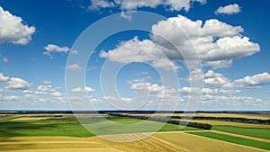 Rural scenic landscape with blue sky and clouds, green fields, yellow meadows in a summer sunny day. Panoramic view from