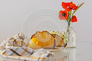 Rural still life with red poppies in glass vase and a plate with biscocho Bizcocho lemon muffin on kitchen table. Sweet photo