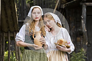 Rural Style Concepts. Pair of Young Beautful Caucasian Girlfriends in Traditional Rural Outfit  Posing With Caly Jar And Bread