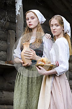 Rural Style Concepts. Two Young Beautful Caucasian Girlfriends in Traditional Rural Outfit  Posing With Caly Jar And Bread