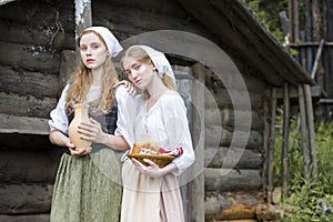 Rural Style Concepts. Two Young Beautful Caucasian Girlfriends in Traditional Rural Outfit  Posing With Caly Jar And Bread