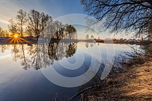 Rural summer sunrise landscape with river and dramatic colorful sky