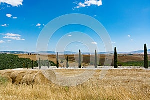 Rural Tuscany landscape with hills, cypresses and haystacks