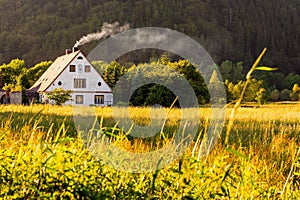 traditional polish country cottage house with smoke from the chimney