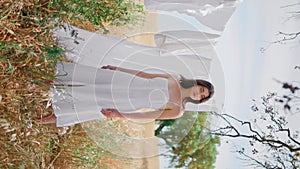 Rural woman drying laundry at wild nature vertical. Summer girl posing rye field