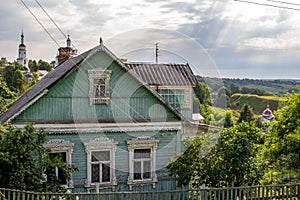 Rural wooden house with carved frames in the background of churches in Maloyaroslavets, Russia