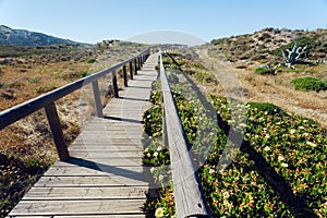 Rural wooden path to village through beautiful natural landscape, Portugal. Green hills in peaceful area of Algarve