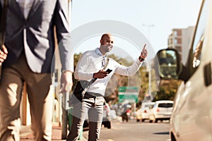 In a rush heading to the office. a handsome young businessman hailing a ride in the city.