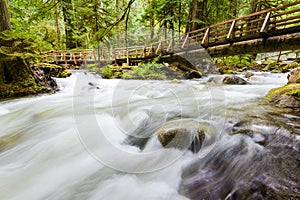 Rushing stream passing under a wooden footbridge