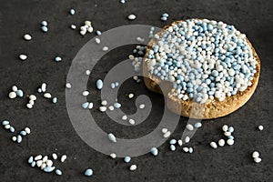 Rusk with blue aniseed balls, muisjes, tradition in the Netherlands to celebrate the birth of a son. Against dark background.