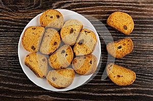 Rusks with raisin in plate, few rusks on wooden table. Top view