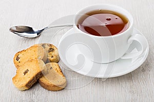 Rusks with raisin, tea in cup with saucer and teaspoon