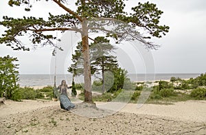 On the coast of the White Sea, a girl swinging on a swing.