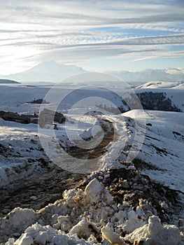 Russia, Caucasia. Road and snow on mountain and blue sky background, vertical view.