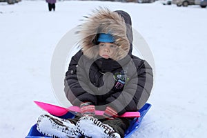 Russia,  a child boy sledding in winter walks on the street in the snow