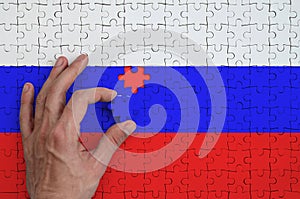 Russia flag is depicted on a puzzle, which the man`s hand completes to fold