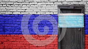 Russia flag painted on brick wall and closed door with medical mask protected