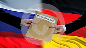 Russia and Germany officials exchanging confidential envelope, flags background