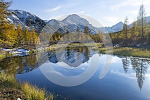 Russia. Magadan Region. A beautiful forest lake against the backdrop of the Big Anngachak mountain range. Autumn in the vicinity