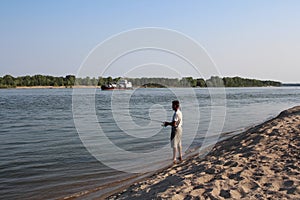 Russia,  a male fisherman with a fishing rod catches fish on the river in summer