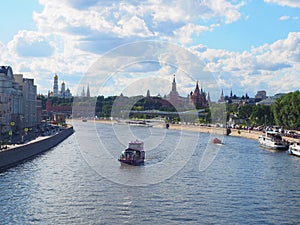 Russia, Moscow - July 2022: View of the  Moscow Kremlin by a sunny cloudy day and Moscow transport: cars and a ship