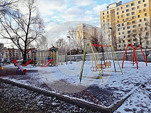 Russia, Moscow, March 2019. Playground covered by snow. Sunny morning. Swings and slides. Early spring. Snow background.