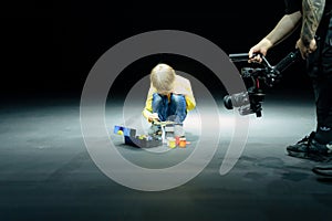 videographer shoots on video camera, as little six year old kid boy painting or colorize or colour model airplane photo