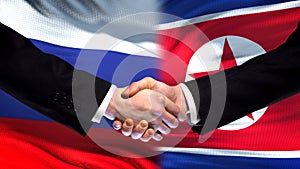 Russia and North Korea handshake, international friendship, flag background