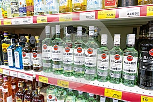 Bacardi bottles of white rum stand on a shelf in a supermarket. Close-up.