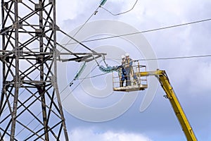 electricians are repairing a high-voltage line against the background of a blue sky