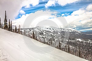 Russia.Sheregesh. Winter mountain landscape. View from the slope of the mountain. Spruce taiga under the snow against the backdrop