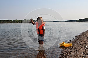 Russia,  a small child boy on the river in a life jacket swims with a toy
