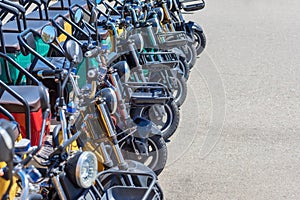 Russia, Sochi 14.05.2022. Multi-colored electric bikes with headlights and baskets stand in a row on an asphalt road on