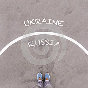 Russia and Ukraine, text on asphalt ground, feet and shoes on floor