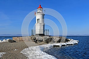 Russia. Vladivostok. The lighthouse of Egersheld1876 year built Tokarevskaya koshka in winter sunny day in Amur bay